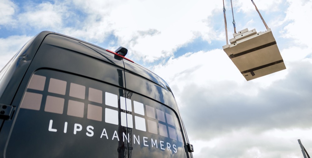 Bedrijfsbus van Lips Aannemers en een hijskraan op de bouwplaats